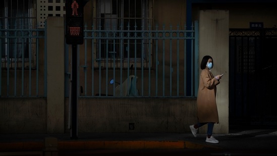 Covid In China: A woman wearing a face mask walks along a street in Beijing.(AP) Covid In China: A woman wearing a face mask walks along a street in Beijing.(AP)