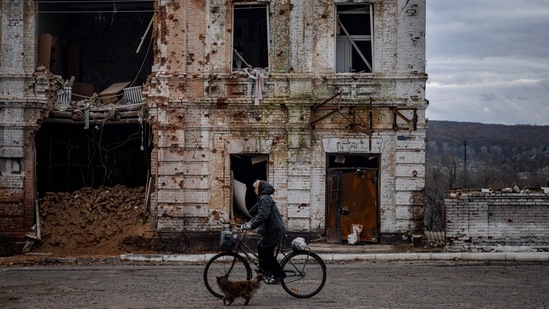 Russia-Ukraine War: A woman rides a bicycle past a damaged building in the town of Kupiansk. (AFP)