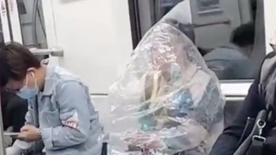 Covid In China: Woman eats banana while being wrapped in plastic bag.