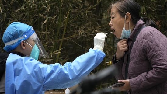 Covid In China: A woman lowers her mask to get swabbed for COVID test in Beijing.(AP)