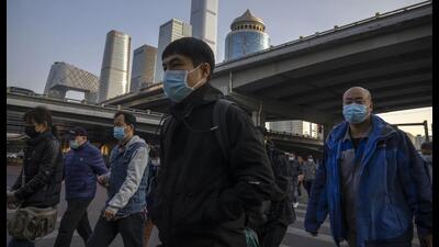 Commuters wearing masks walk along a street in the central business district in Beijing. (AP) Commuters wearing masks walk along a street in the central business district in Beijing. (AP)