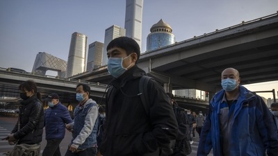 Covid In China: Commuters wearing face masks walk along a street in the central business district in Beijing. (AP)