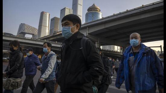 Commuters wearing masks walk along a street in the central business district in Beijing. (AP)