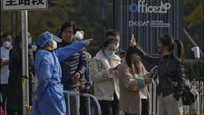 A woman (right) wearing a mask shows her health check QR code as she and others line up to get their routine Covid-19 throat swabs at a testing site in Beijing, on Tuesday. (AP) A woman (right) wearing a mask shows her health check QR code as she and others line up to get their routine Covid-19 throat swabs at a testing site in Beijing, on Tuesday. (AP)