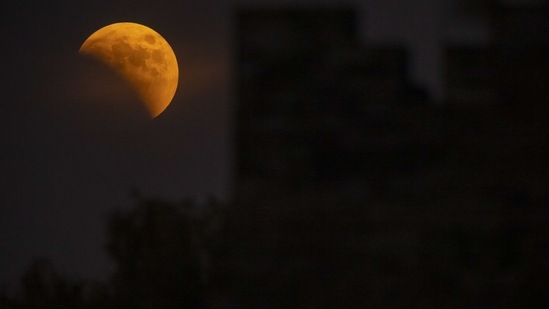 The moon rises behind a corner tower along the outer walls of the Forbidden City during a lunar eclipse in Beijing on November 8.(AP)