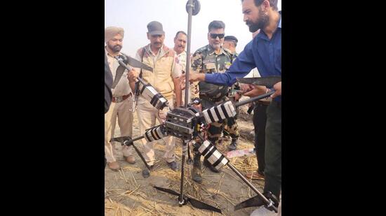 Punjab Police and Border Security Force personnel examining the hexa-copter drone that was brought down by BSF personnel near a border village in Ferozepur district on Tuesday night. (HT Photo)