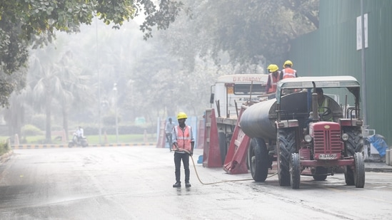 Public Works Department (PWD) workers use 'dust suppressants' sprinkling water to control road dust in view of rising air pollution, in New Delhi on Tuesday. (ANI Photo)(Amit Sharma)
