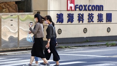 Covid In China: People walk past the logo of Foxconn outside the company's building. (Reuters)