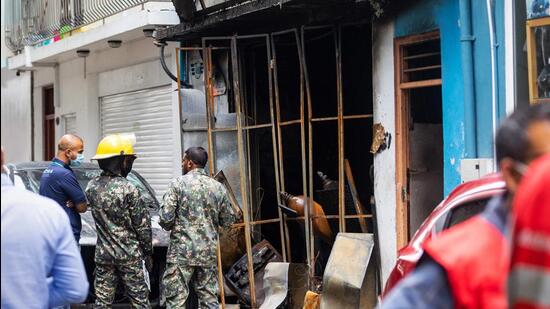 Firefighters and emergency personnel stand outside a building after a major fire swept through cramped living quarters of foreign workers in the Maldives capital Male on November 10, 2022. (AFP)