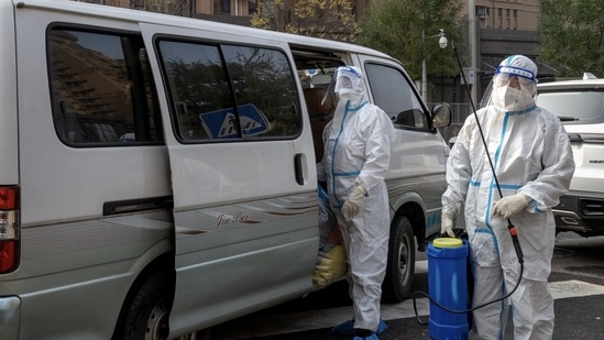 Covid In China: Workers in protective gear at a neighborhood placed under lockdown due to Covid-19 in Beijing, China.(Bloomberg)