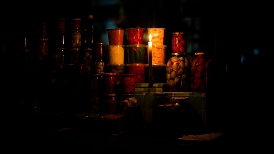 Russia-Ukraine War: A candle illuminates a market pickle food stall during a power outage in central Kyiv.(AP)