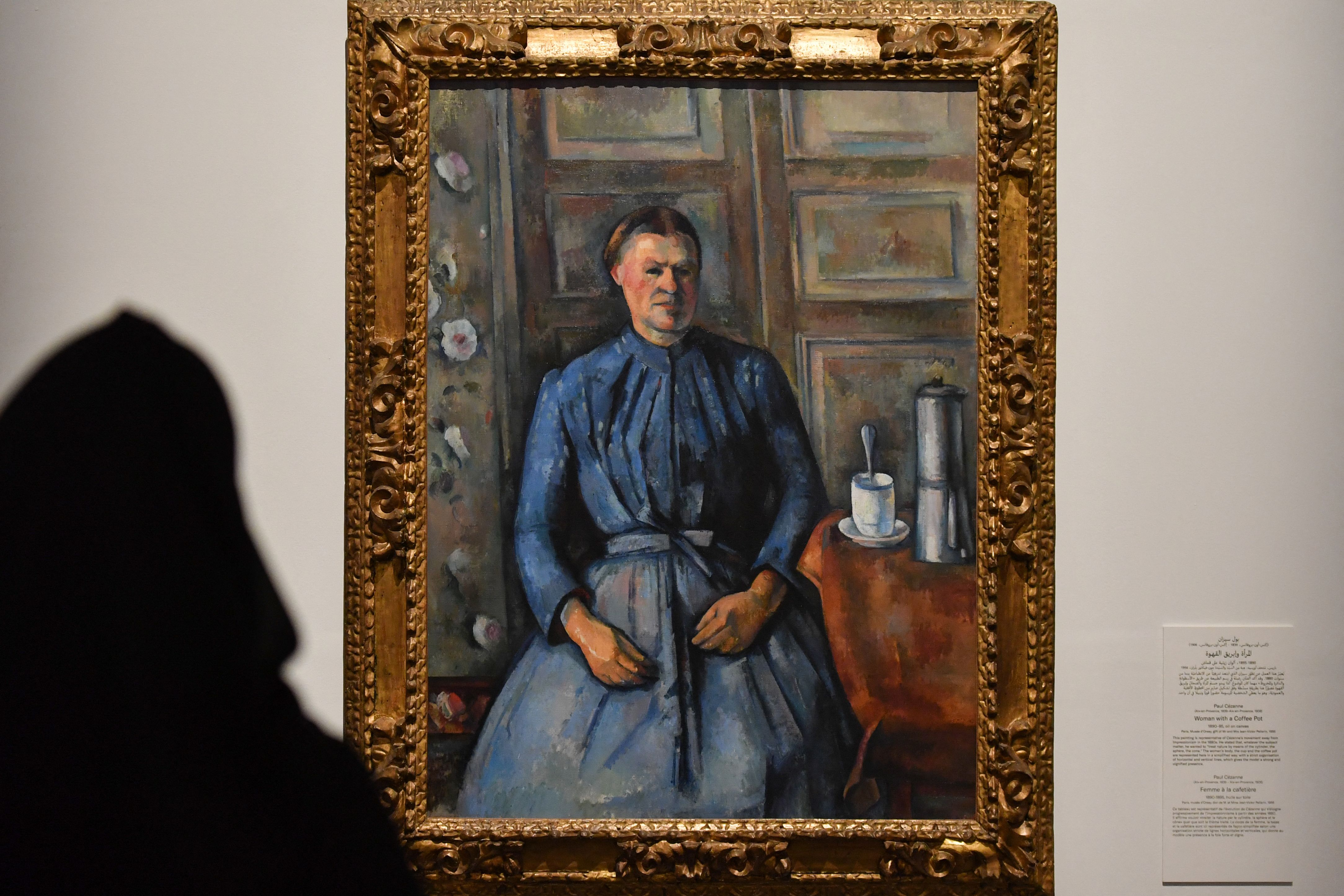 A visitor looks at Paul Cezanne's masterpiece Woman with a Coffee Pot displayed at the exhibition "Impressionism: Pathways to Modernity" at the Louvre Museum Abu Dhabi in the Gulf emirate, (AFP)