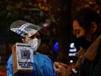 A worker in a protective suit guides people to scan health QR code at a nucleic acid test booth for the coronavirus disease in Beijing, China on November 11.