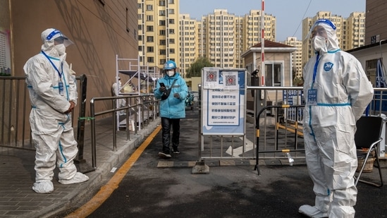 Workers in protective gear at a neighborhood placed under lockdown due to Covid-19 in Beijing, China, November 10.(Bloomberg) Workers in protective gear at a neighborhood placed under lockdown due to Covid-19 in Beijing, China, November 10.(Bloomberg)