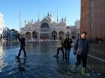 People wade through water on a flooded St. Mark's Square during seasonal high water in Venice, Italy. Lagoon city Venice delays charging tourists for daily visits 