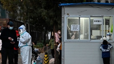 Covid In China: A health worker talks with a man while a health worker inside a nucleic acid testing station gets a swab sample. (AFP) Covid In China: A health worker talks with a man while a health worker inside a nucleic acid testing station gets a swab sample. (AFP)