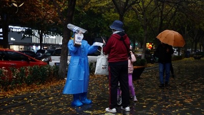 Covid In China: A worker in a protective suit guides people to scan health QR code at a nucleic acid test booth. (Reuters)