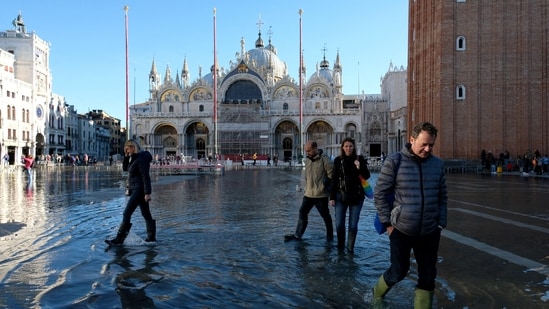 People wade through water on a flooded St. Mark's Square during seasonal high water in Venice, Italy. Lagoon city Venice delays charging tourists for daily visits (REUTERS/Manuel Silvestri)