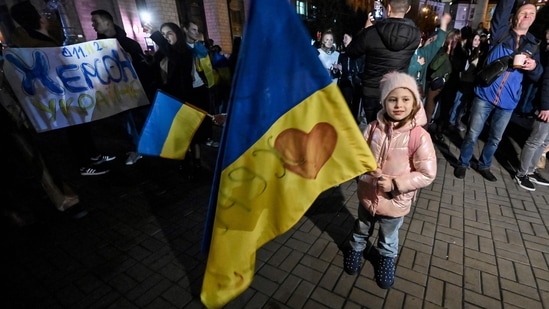 Russia-Ukraine War: A child holds a Ukranian flag as people gather in Maidan square to celebrate.(AFP)