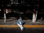 Covid In China: A pandemic prevention worker in a protective suit rests in the sun.