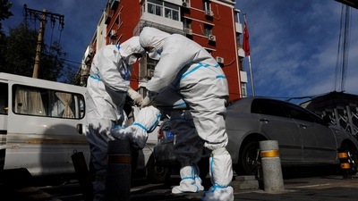 Covid In China: Pandemic prevention workers in protective suits prepare to enter an apartment compound that was placed under lockdown. (Reuters)