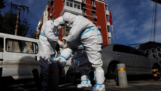 Covid In China: Pandemic prevention workers in protective suits prepare to enter an apartment compound that was placed under lockdown.(Reuters)