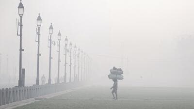 A worker walks through a lawn near India Gate, shrouded in smog, in New Delhi. (PTI Photo) A worker walks through a lawn near India Gate, shrouded in smog, in New Delhi. (PTI Photo)