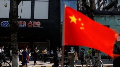 A China's flag flutters near people lining up to get tested at a makeshift nucleic acid testing site. (Reuters File)