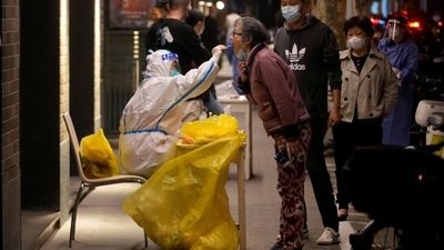 Covid In China: A medical worker in a protective suit collects a swab from a resident for nucleic acid testing. (Reuters)