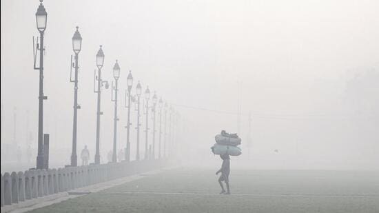 A worker walks through a lawn near India Gate, shrouded in smog, in New Delhi. (PTI Photo)