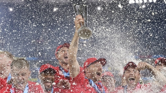 England's captain Jos Buttler, center, holds the trophy as players spray champagne while they celebrate after defeating Pakistan in the final (AP)
