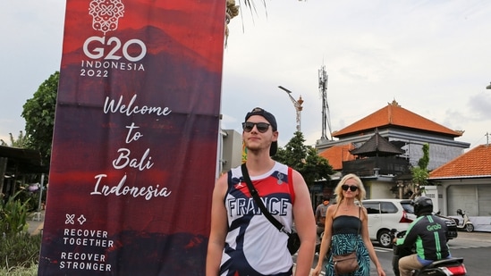 Tourists walk past a G20 banner in Nusa Dua, Bali, Indonesia. The dozens of world leaders and other dignitaries travelling to Bali for the G-20 summit will be drawing a welcome spotlight on the revival of the tropical island's ailing tourism sector after a two-year closure to foreign travelers due to the pandemic. (AP Photo/Firdia Lisnawati)