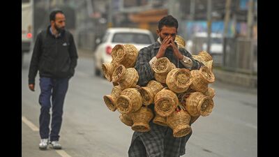 A vendor carries Kangri, earthen pots filled with embers and woven with willow wicker, used to stave off the cold in Srinagar on Tuesday. (AFP) A vendor carries Kangri, earthen pots filled with embers and woven with willow wicker, used to stave off the cold in Srinagar on Tuesday. (AFP)