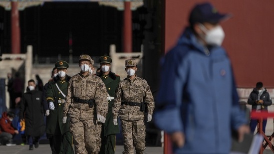 Soldiers and paramilitary policemen wearing face masks march through masked visitors.(AP)