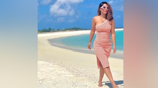For the pictures, Hina slipped into a beach-ready ensemble featuring ribbed knit detail. The sleeveless dress also comes with red and white printed stripes, a one-shoulder neckline, a figure-hugging silhouette highlighting Hina's curves, a cut-out on the side, a risqué thigh-high slit, and a knee-length hemline.(Instagram)