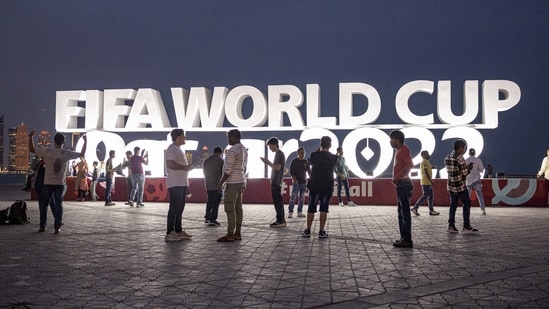 People are pictured in front of a FIFA World Cup Qatar 2022 sign ahead of the World Cup.(REUTERS)