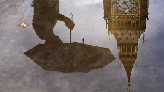 Britain: A woman with an umbrella and the Elizabeth Tower also known as Big Ben are reflected in a puddle in London. (AP)