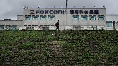 This file photo taken on May 6, 2022 shows a man walking past the Foxconn headquarters in Tucheng district, New Taipei City. Taiwanese electronics giant and iPhone manufacturer Foxconn warned that its last quarter earnings this year would take a hit from the coronavirus lockdowns affecting its assembly lines in the Chinese city of Zhengzhou. (AFP) This file photo taken on May 6, 2022 shows a man walking past the Foxconn headquarters in Tucheng district, New Taipei City. Taiwanese electronics giant and iPhone manufacturer Foxconn warned that its last quarter earnings this year would take a hit from the coronavirus lockdowns affecting its assembly lines in the Chinese city of Zhengzhou. (AFP)