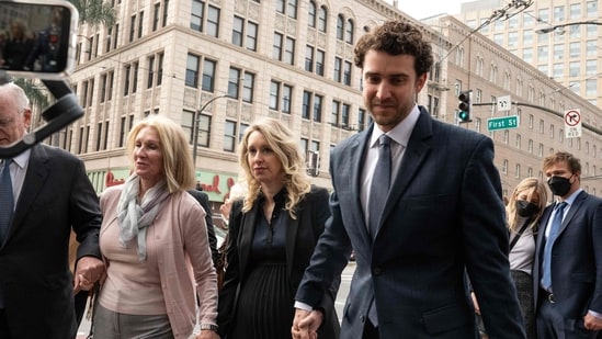 Elizabeth Holmes(middle), founder and former CEO of blood testing and life sciences company Theranos, walks with her mother and partner Billy Evans for her sentence hearing on Friday.(AFP )
