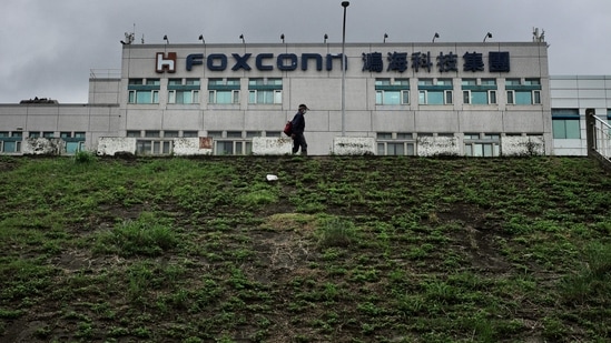 This file photo taken on May 6, 2022 shows a man walking past the Foxconn headquarters in Tucheng district, New Taipei City. Taiwanese electronics giant and iPhone manufacturer Foxconn warned that its last quarter earnings this year would take a hit from the coronavirus lockdowns affecting its assembly lines in the Chinese city of Zhengzhou.(AFP)