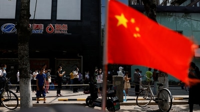A China's flag flutters near people lining up to get tested at a makeshift nucleic acid testing site. (File image)