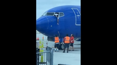 Pilot leaning out of plane's window to get passenger's forgotten phone from crew. (Facebook/Southwest Airlines) Pilot leaning out of plane's window to get passenger's forgotten phone from crew. (Facebook/Southwest Airlines)