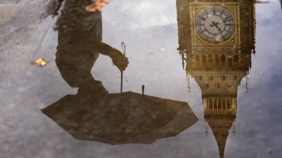 UK Weather: A woman with an umbrella and the Elizabeth Tower also known as Big Ben are reflected in a puddle in London. (AP)