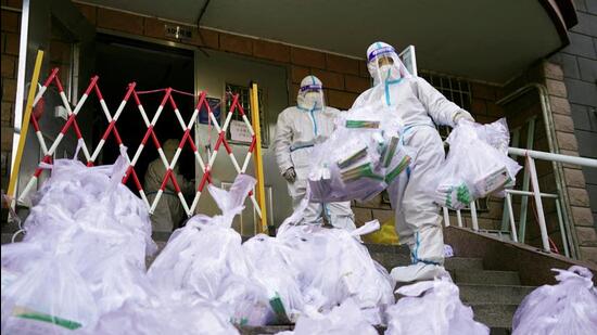 Workers in protective suits prepare to enter a building under lockdown to distribute antigen testing kits for Covid-19, at a residential compound in Beijing's Chaoyang district, China, on Monday. (REUTERS)