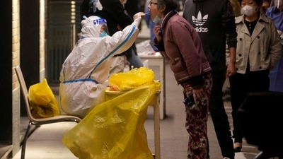 Covid In Shanghai: A medical worker in a protective suit collects a swab from a resident. (Reuters)
