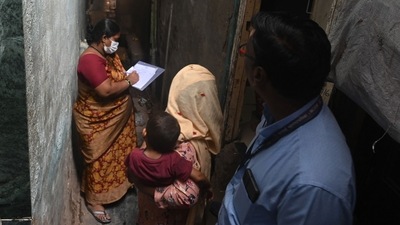 A woman (C) cradling her child interacts with municipal staff during a survey inside a slum following a measles outbreak in Mumbai on Wednesday. (AFP) A woman (C) cradling her child interacts with municipal staff during a survey inside a slum following a measles outbreak in Mumbai on Wednesday. (AFP)