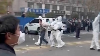Security personnel in protective clothing seen taking away a person during protest at the factory compound operated by Foxconn Technology Group who runs the world's biggest Apple iPhone factory in Zhengzhou in China. (AP) Security personnel in protective clothing seen taking away a person during protest at the factory compound operated by Foxconn Technology Group who runs the world's biggest Apple iPhone factory in Zhengzhou in China. (AP)