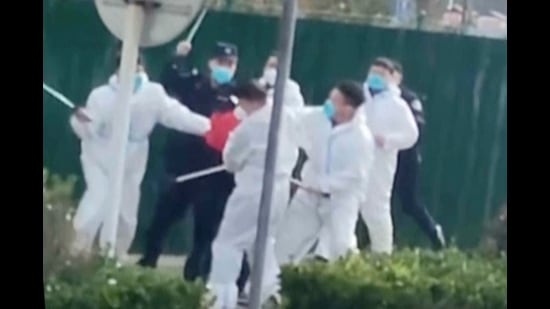 Security personnel in protective clothing attack a protester with clubs after he grabbed a metal pole that had been used to strike him during protest at the factory compound operated by Foxconn Technology Group who runs the world's biggest Apple iPhone factory in Zhengzhou in central China's Henan province (AP)