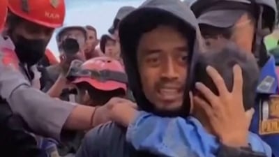 This frame grab taken from mobile phone video footage released by Bogor Administration shows a six-year-old boy being pulled out of the rubble in Cianjur, West Java on November 23, 2022 (AFP)