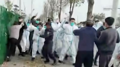Security personnel in protective clothing attack a man during protest at the factory compound operated by Foxconn Technology Group who runs the world's biggest Apple iPhone factory in Zhengzhou in central China's Henan province. (AP)
